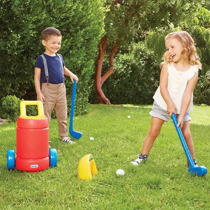 Boy and girl toddlers swinging colorful plastic golf clubs at an oversized golf ball.