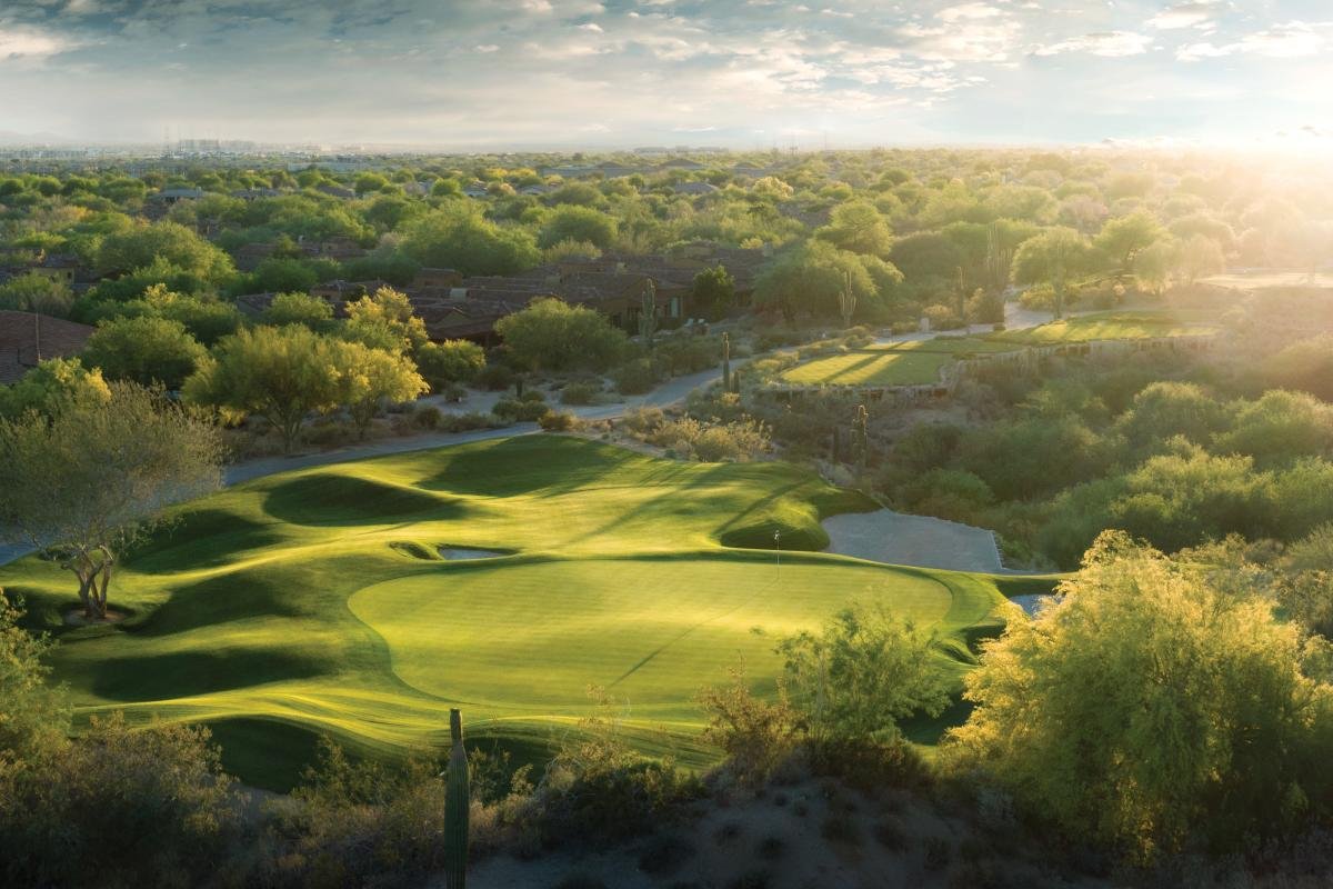 Hole 11 on Grayhawk Golf Club's Talon course in Scottsdale: a rolling green in the Sonoran Desert with saguaros, palo verde, and the valley beyond at golden hour.