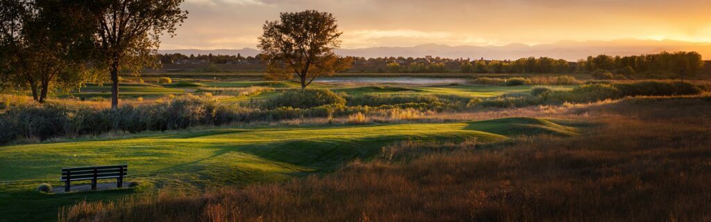CommonGround Golf Course fairway and green at sunset with Front Range mountains beyond.