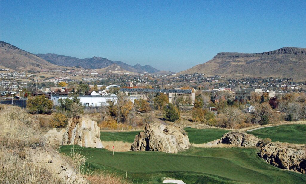 Fossil Trace Golf Course in Golden with rock pillars, a green, and Table Mountain beyond.