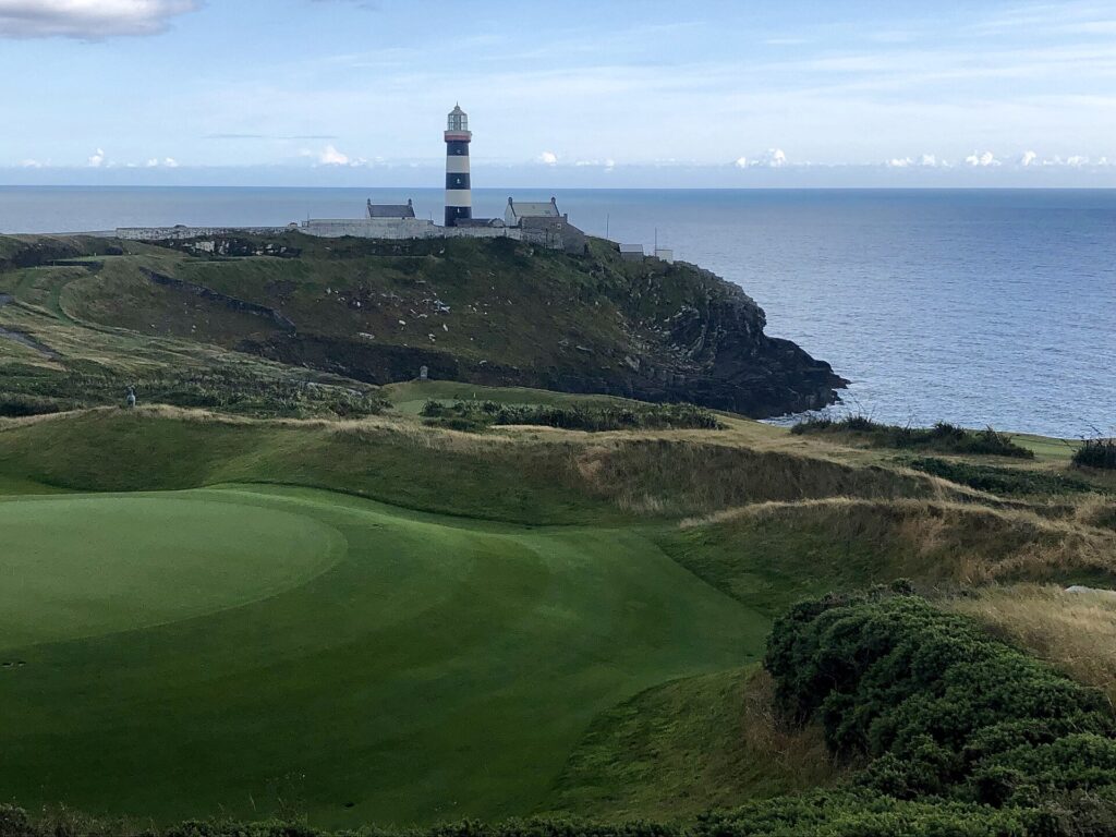 Old Head Golf Links green with the Old Head of Kinsale lighthouse beyond.