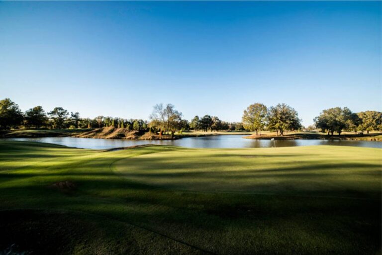 Green beside a pond at Mirimichi Golf Course near Memphis under a clear sky.