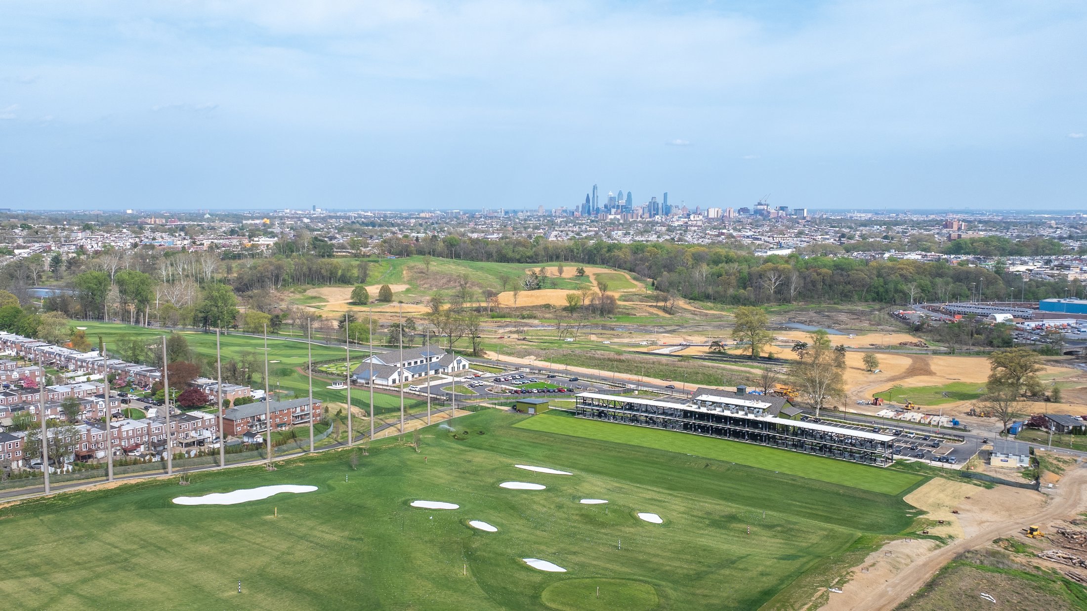 Aerial view of the Cobbs Creek Golf Campus driving range with the Philadelphia skyline beyond